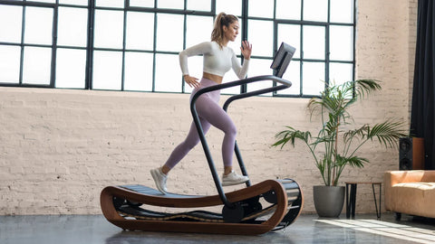 Woman running on the self-powered NOHRD SpringBok in her home gym.