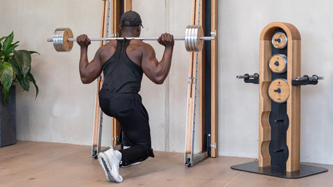 Man lifting weights from the NOHRD WeightTower using a NOHRD SquatRack in his at-home gym.